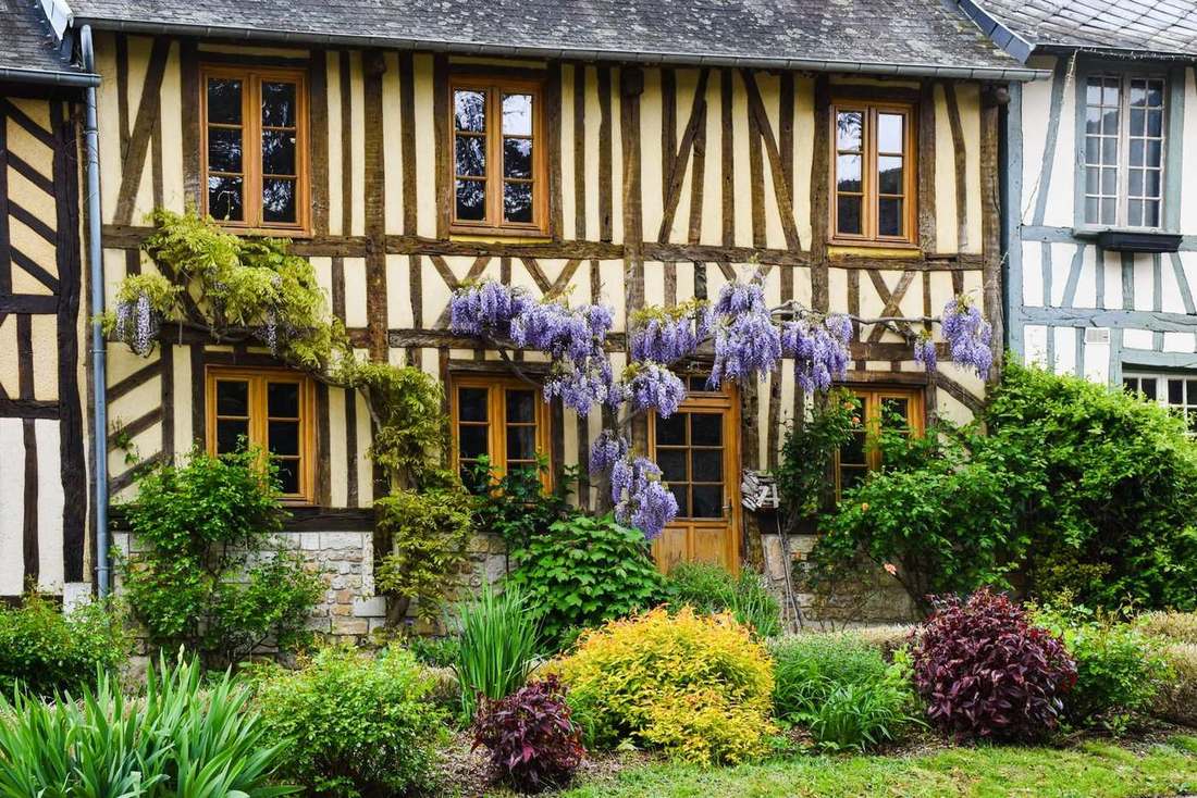 Maison à colombages du Pays d'Auge entourée d'un jardin clos planté d'arbustes et de massifs